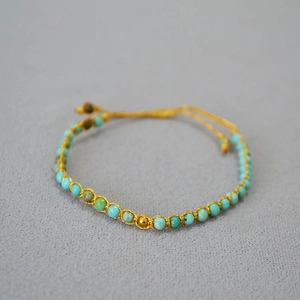 Détail d'un bracelet bohème fait main avec perles turquoise et fil tissé doré