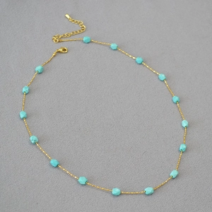 Detail of gold chain necklace with turquoise beads featuring adjustable lobster clasp