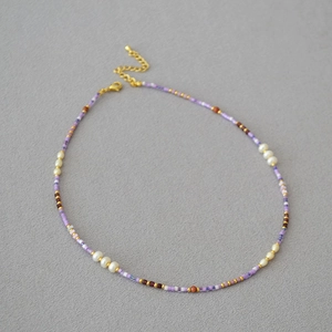Detail of handmade beaded necklace featuring violet beads and freshwater pearls