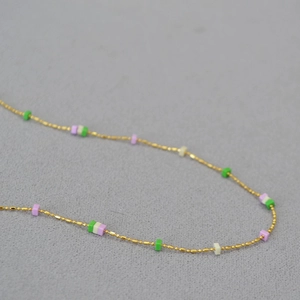 Close-up of thin gold-plated brass chain with colorful geometric square stone beads