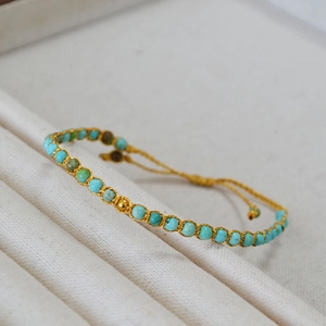 Détail du bracelet en perles turquoise avec tissage doré et cordon de serrage réglable