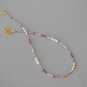 Detail of handmade beaded necklace with violet seed beads and white freshwater pearls