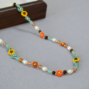 Détail d'un collier de perles fait main avec tournesols et perles naturelles