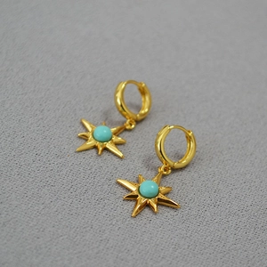 Vintage gold-plated brass starburst earrings featuring turquoise inlay on a grey background