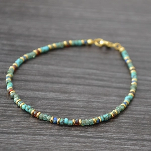 Macro shot of bohemian beads in teal, blue, and brown with gold spacers and lobster clasp