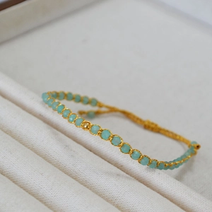 Vue détaillée de perles turquoise tissées de fil doré avec un nœud coulissant ajustable