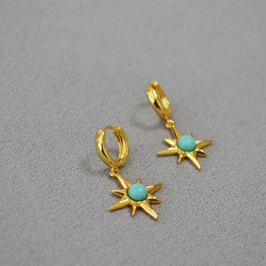 Macro detail of gold starburst earrings featuring inlaid turquoise beads and brass plating
