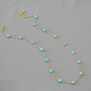 Close-up of gold beaded chain necklace with faceted turquoise stone beads and lobster clasp