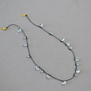 Dettaglio della collana in cordino nero con cristalli di zircone e chiusure dorate