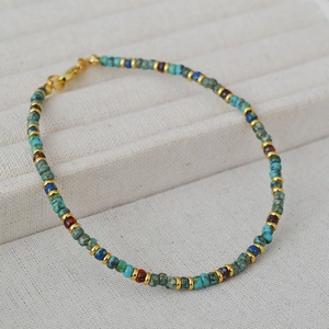 Macro detail of Bohemian handmade beaded bracelet with antique beads and golden lobster clasp
