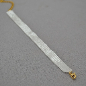 Close-up of hand-woven white square beads necklace with golden lobster clasp and chain