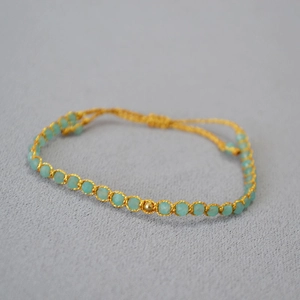 Détail d'un bracelet de perles tissé main avec pierres turquoise et fil dore