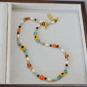 Détail du collier de perles avec fleurs colorées et fermoir mousqueton doré