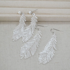 Detailed view of handmade white beaded feather earrings with pearls in bohemian style