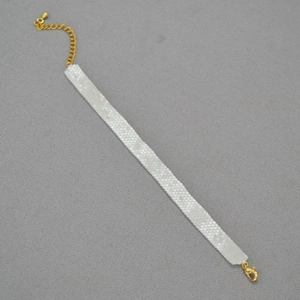 Elegant white beaded choker necklace with gold clasp and adjustable chain on grey surface