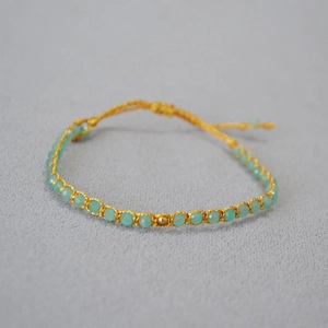 Détail macro d'un bracelet tissé en perles turquoise et fil de soie doré élégant