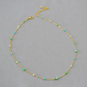 Close-up of golden bead chain with colorful cubic stone beads and lobster clasp closure