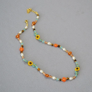 Détail du collier de perles avec fleurs de tournesol et pierres colorées