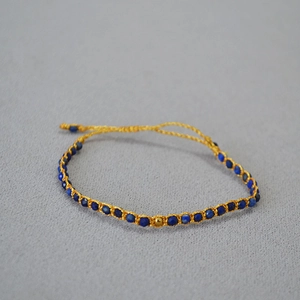 Détail d'un bracelet tissé main avec perles de lapis-lazuli et finitions fil doré