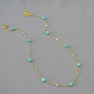Detail of gold chain necklace featuring faceted turquoise beads and silver accents