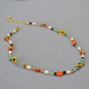 Détail d'un collier de perles fait main avec tournesols et chaîne dorée réglable