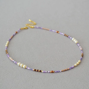 Detail of handmade violet seed bead necklace with white pearls and gold metal clasp