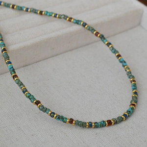 Detailed macro view of Bohemian beaded necklace with turquoise and golden metal spacers