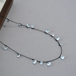 Dettaglio della collana in cordino nero con ciondoli a fiore in zircone scintillante