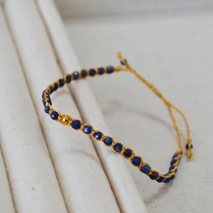 Détail d'un bracelet bohème fait main avec perles de lapis-lazuli bleu foncé et fil doré