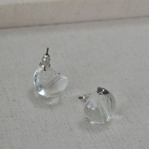 Macro detail of clear drop-shaped glass earrings with polished silver metal posts