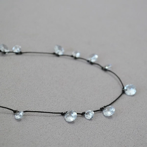 Dettaglio dei cristalli sfaccettati su una collana in corda di cuoio nero annodato