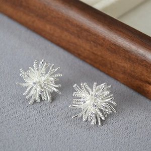 Macro shot of silver fireworks stud earrings with zircon stones on grey fabric background