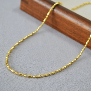 Close-up of a delicate gold-plated bead chain necklace with polished oval beads