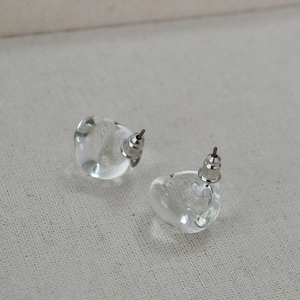 Macro shot of clear teardrop glass earrings on textured fabric with silver studs