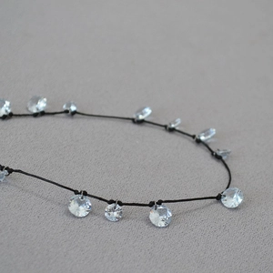 Dettaglio macro di perle di cristallo sfaccettate su cordino nero annodato con design