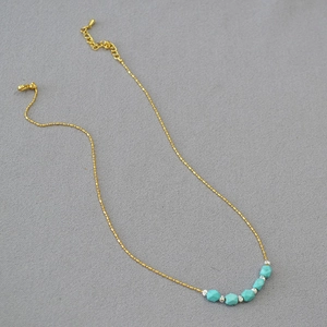 Detail of gold ball chain necklace with turquoise faceted beads and lobster clasp closure