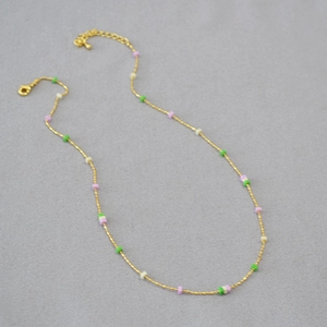 Close-up of gold chain necklace with colorful square beads and lobster clasp