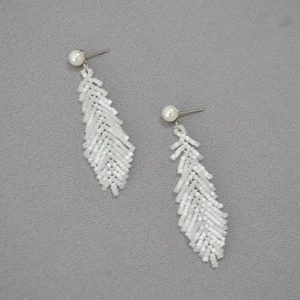 Detailed macro view of handmade white beaded feather earrings with elegant pearl studs