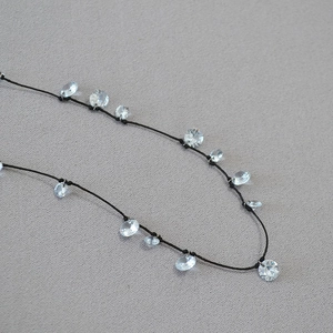 Dettaglio della collana in cordino nero annodato con perline di cristallo sfaccettato