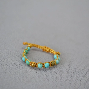 Détail d'un bracelet bohème tissé à la main avec perles turquoise et fil doré