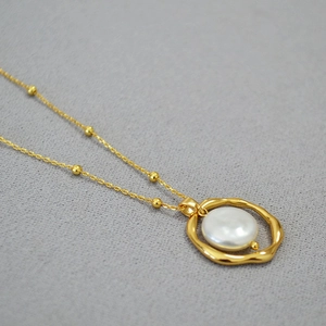 Macro shot of irregular golden hoop pendant with baroque pearl on a fine beaded necklace