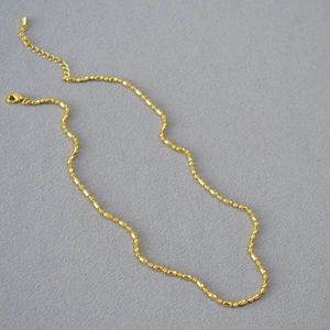 Detail of minimalist brass gold plated rice bead necklace with lobster clasp