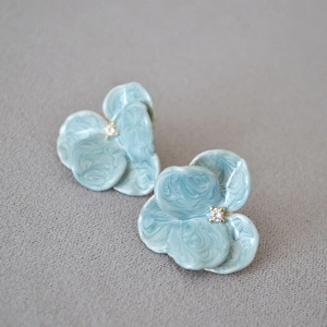 Detailed macro of light blue enamel orchid studs with white zircon and gold base