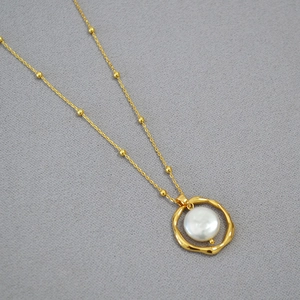 Macro detail of Baroque freshwater pearl pendant with irregular gold geometric ring