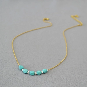 Detailed close-up of turquoise hexagonal beads on a gold chain necklace with silver spacers
