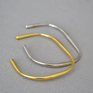 Detail von unregelmäßigen Wellenarmreifen in Gold und Silber mit dynamischen Linien