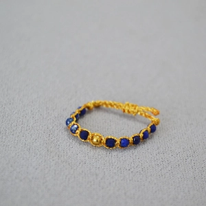 Vue macro d'une bague bohème tissée main en perles de lapis-lazuli et bille d'or