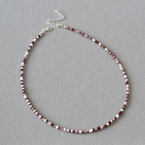 Detail of Miyuki bead necklace featuring red and purple beads with gold spacers and clasp