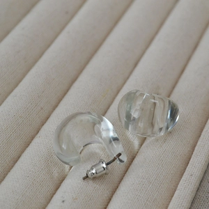 Macro detail of transparent chunky glass drop earrings on a beige velvet jewelry tray