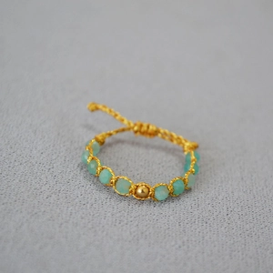 Détail d'une bague tressée à la main avec perles turquoise et accents dorés
